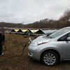 Leaf plugged into Tesla to J1772 adapter. Charger next to solar panels. Drive on sunshine.