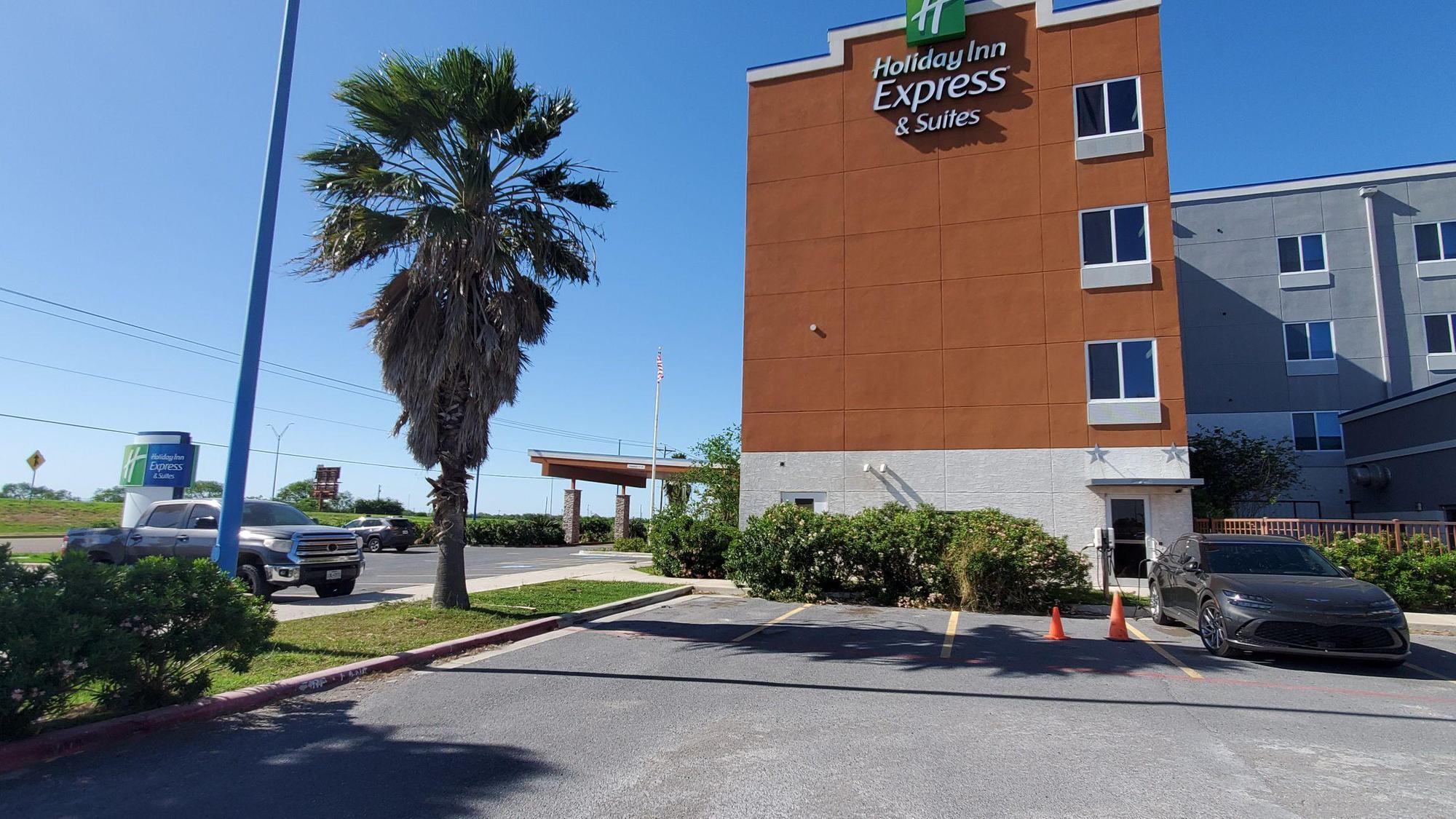 Street entrance at far left, building entrance at center, charging stations at right.